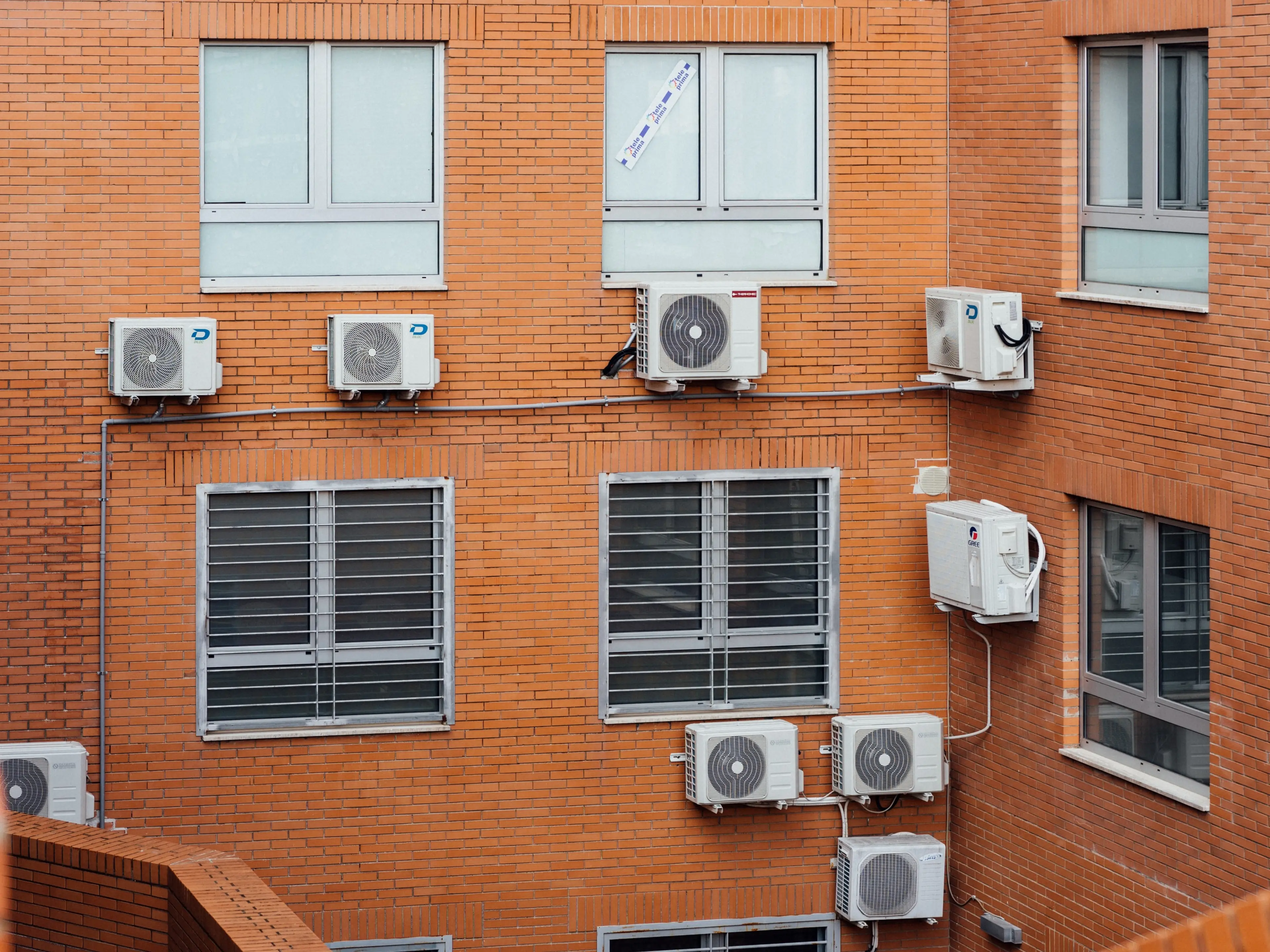 Brown concrete building with air conditioners on the wall.